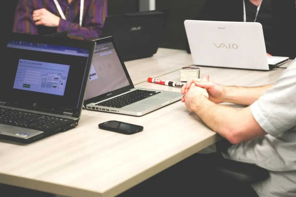 Pessoas trabalhando em notebooks numa mesa compartilhada